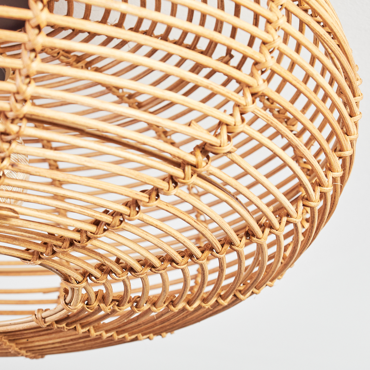 Nahaufnahme eines gewebten Rattan-Lampenschirms. Der Schirm ist hellbraun und hat eine abgerundete Form, mit weißem Hintergrund.