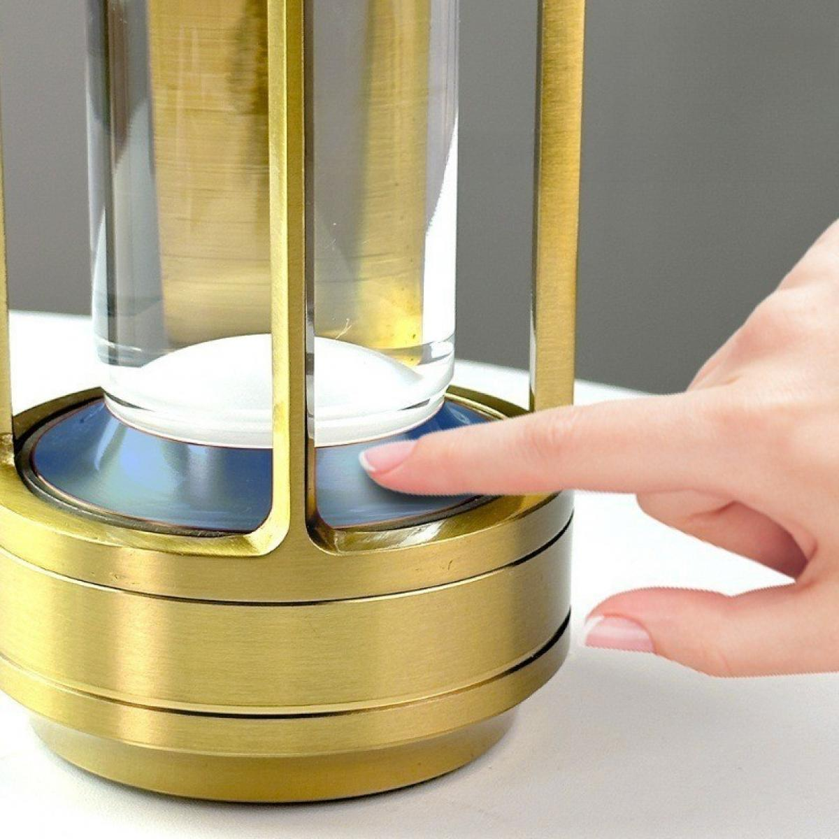 Eine Hand drückt einen Knopf auf einer goldfarbenen Sanduhr. Die Sanduhr hat einen blauen Sockel und einen klaren Glasteil.