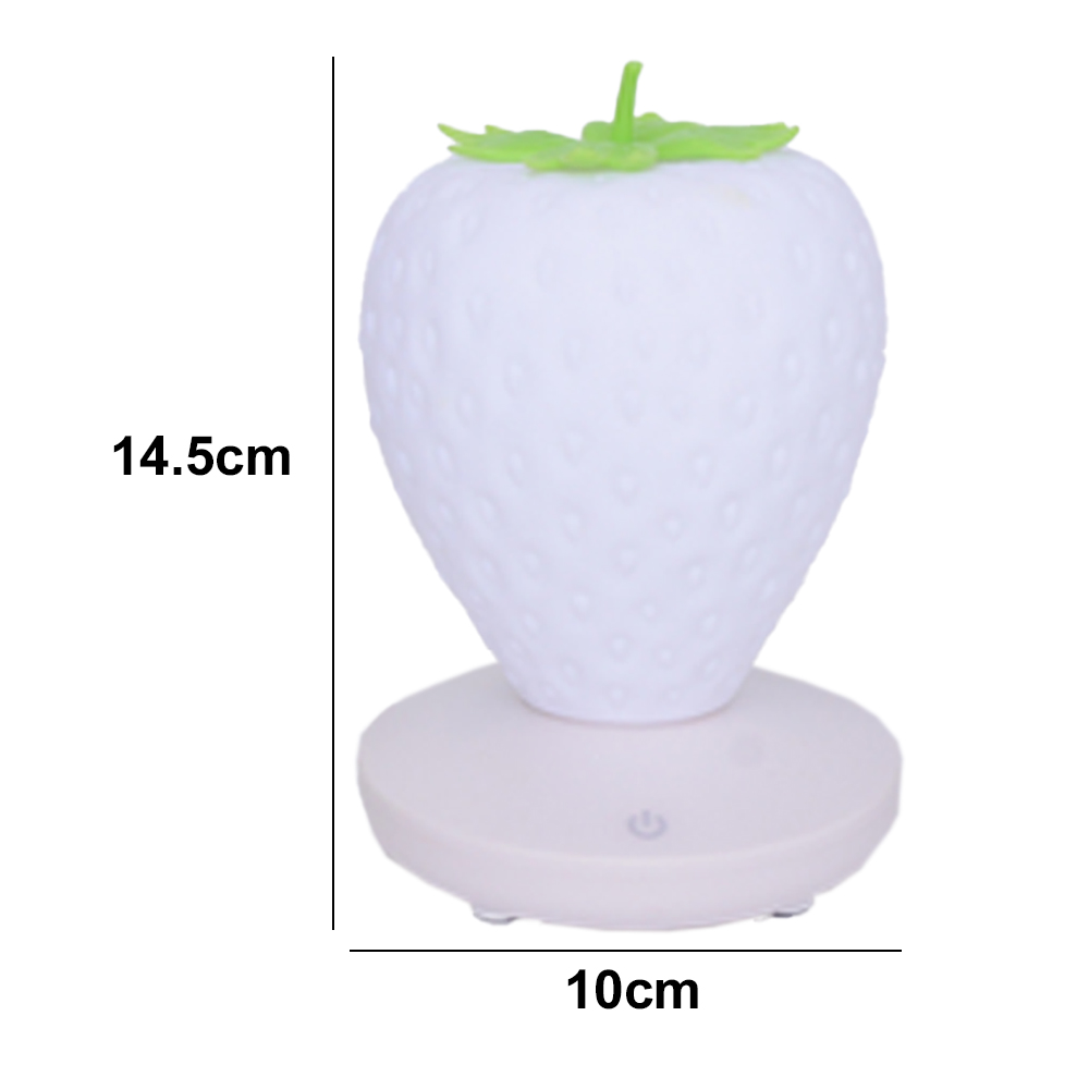 Eine weiße erdbeerförmige Lampe mit grünen Blättern oben. Sie steht auf einem runden Sockel. Maße: 14,5 cm hoch, 10 cm breit.