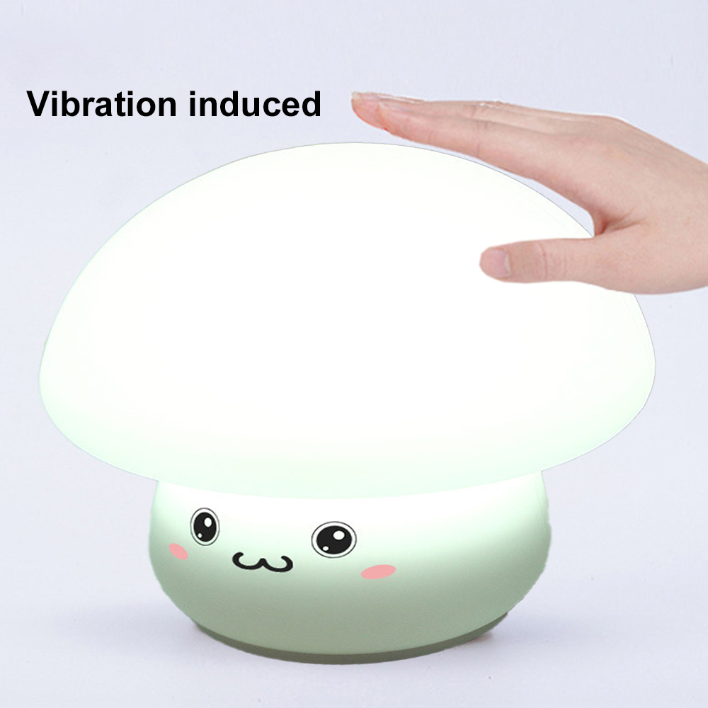 Eine pilzförmige Lampe mit lächelndem Gesicht. Eine Hand berührt die Lampe. Die Lampe leuchtet und der Text 'Vibration induziert' ist sichtbar.