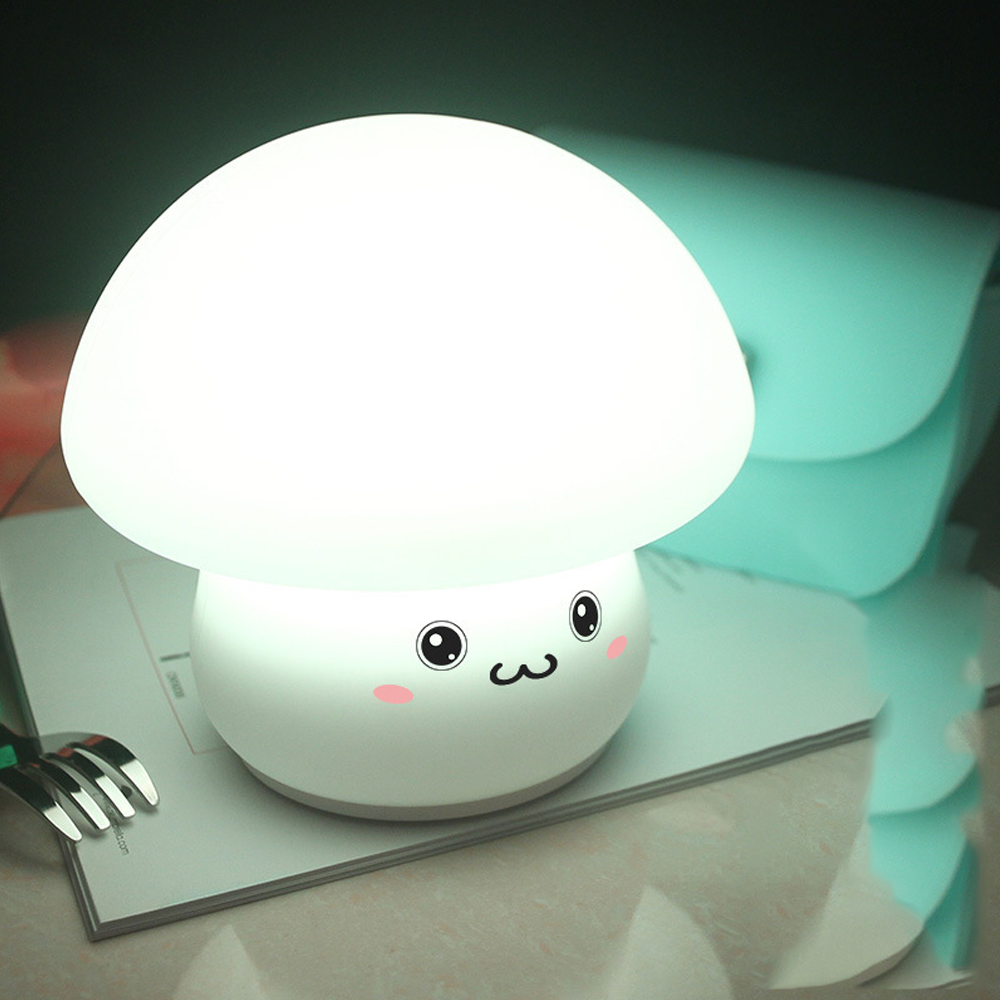 Eine pilzförmige Lampe mit einem lächelnden Gesicht auf einem Tisch mit einer Gabel. Im Hintergrund ist eine hellblaue Tasche zu sehen.