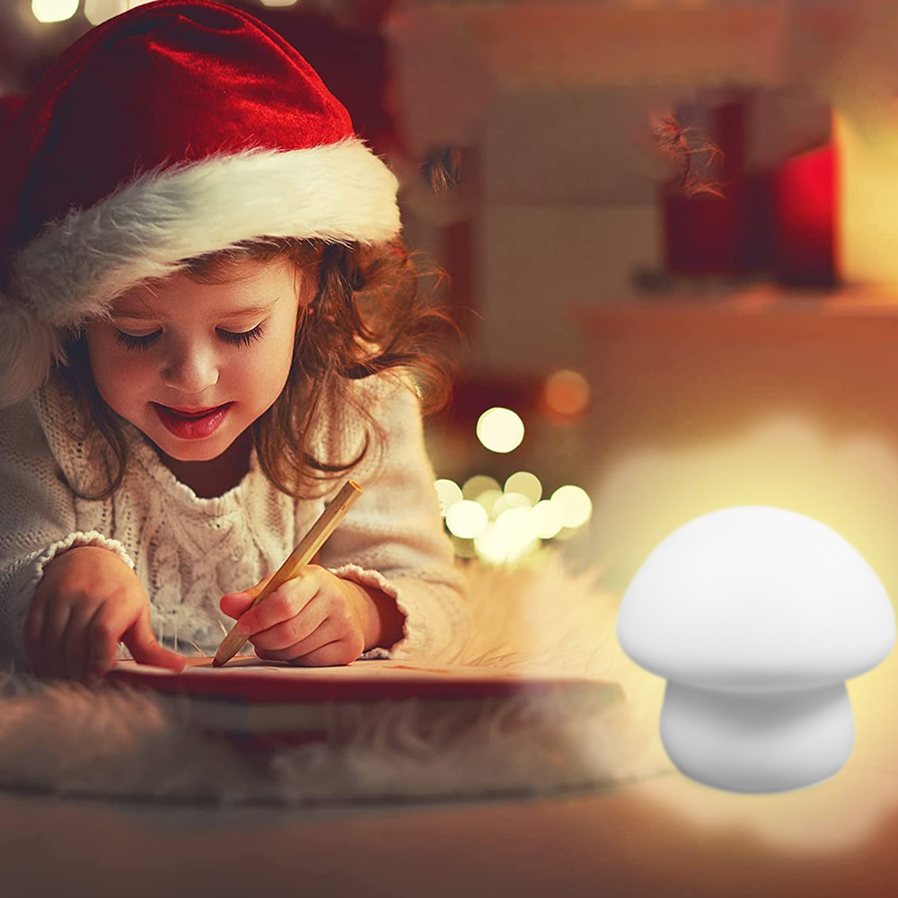 Ein Mädchen mit Weihnachtsmütze schreibt mit einem Bleistift auf Papier. Eine weiße Pilzlampe ist im Vordergrund, und Weihnachtsbeleuchtung im Hintergrund.