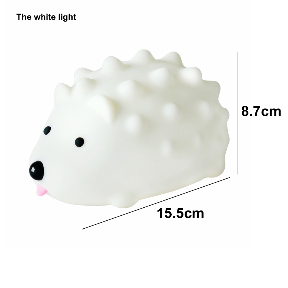 Ein weißes, igelförmiges Licht mit schwarzen Augen und einer rosa Zunge. Abmessungen: 15,5 cm lang, 8,7 cm hoch. Text: Das weiße Licht.