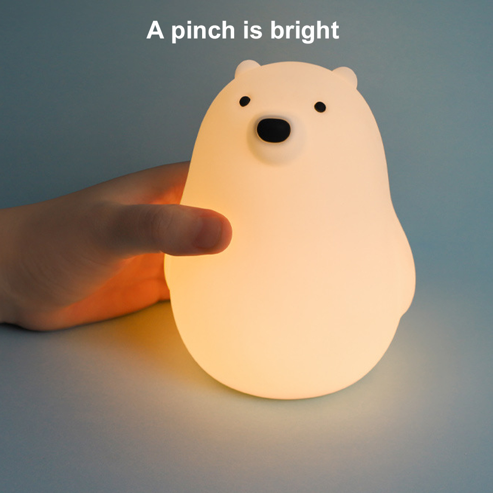 Eine leuchtende Eisbärlampe wird von einer Hand gehalten. Der Bär hat schwarze Augen und eine Nase. Der Hintergrund ist hellblau.