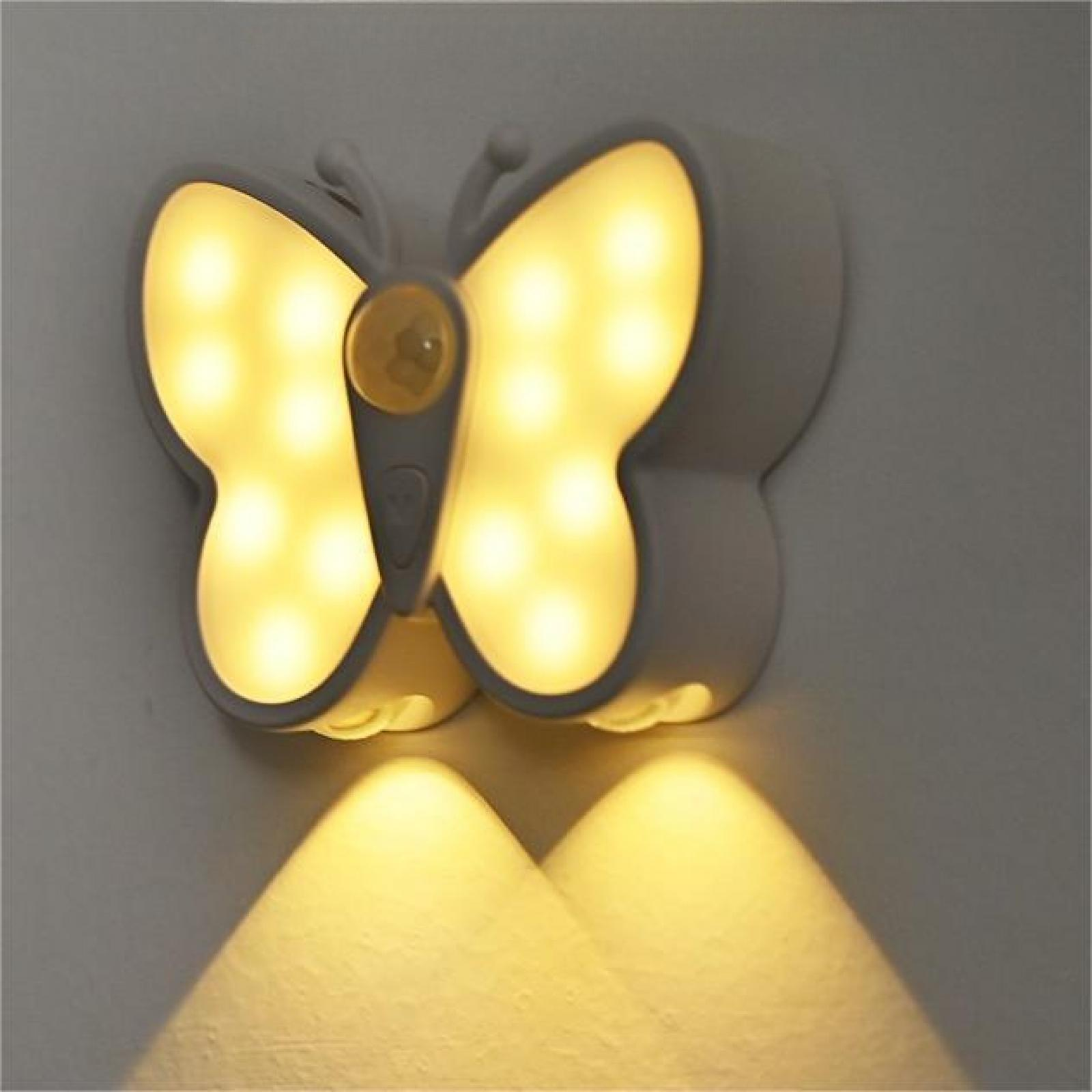 Ein schmetterlingsförmiges Nachtlicht mit gelben Lichtern ist an einer grauen Wand befestigt. Das Licht scheint nach unten.