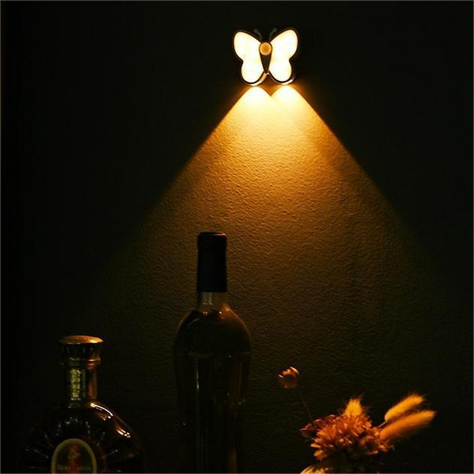 Ein schmetterlingsförmiges Licht scheint auf eine Wand. Flaschen und eine Blume befinden sich im unteren Teil.