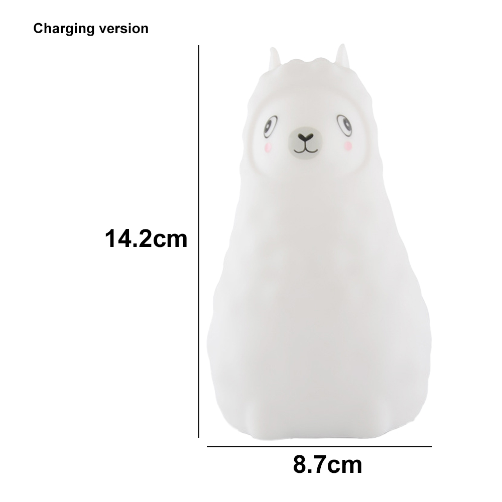 Eine weiße Lampe in Lamaform mit schwarzen Augen und rosigem Rouge. Die Maße sind 14,2 cm hoch und 8,7 cm breit. Der Text lautet 'Charging version'.