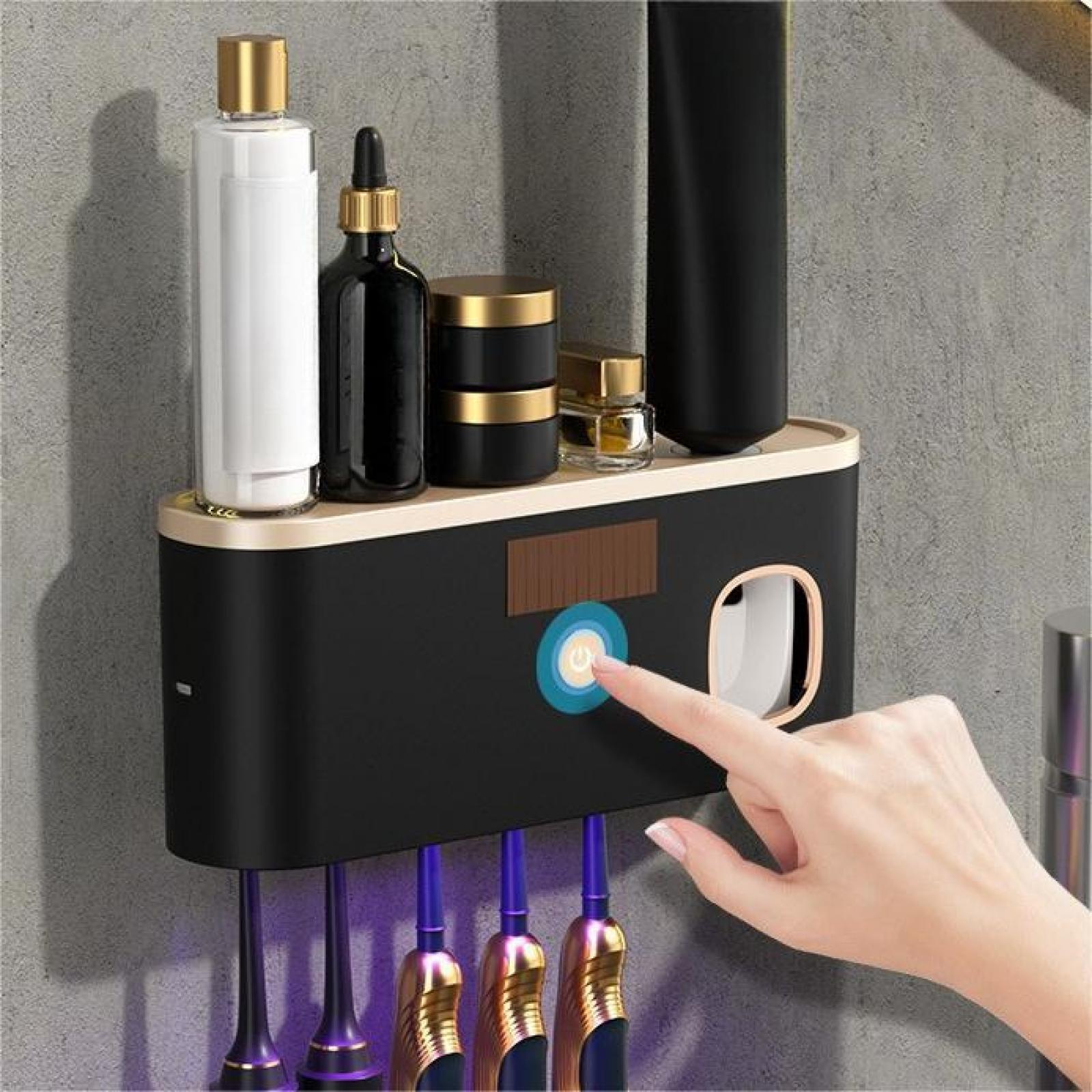 Eine Hand berührt einen Power-Knopf an einem schwarzen und goldenen Zahnbürstenhalter mit Toilettenartikeln und Zahnbürsten.