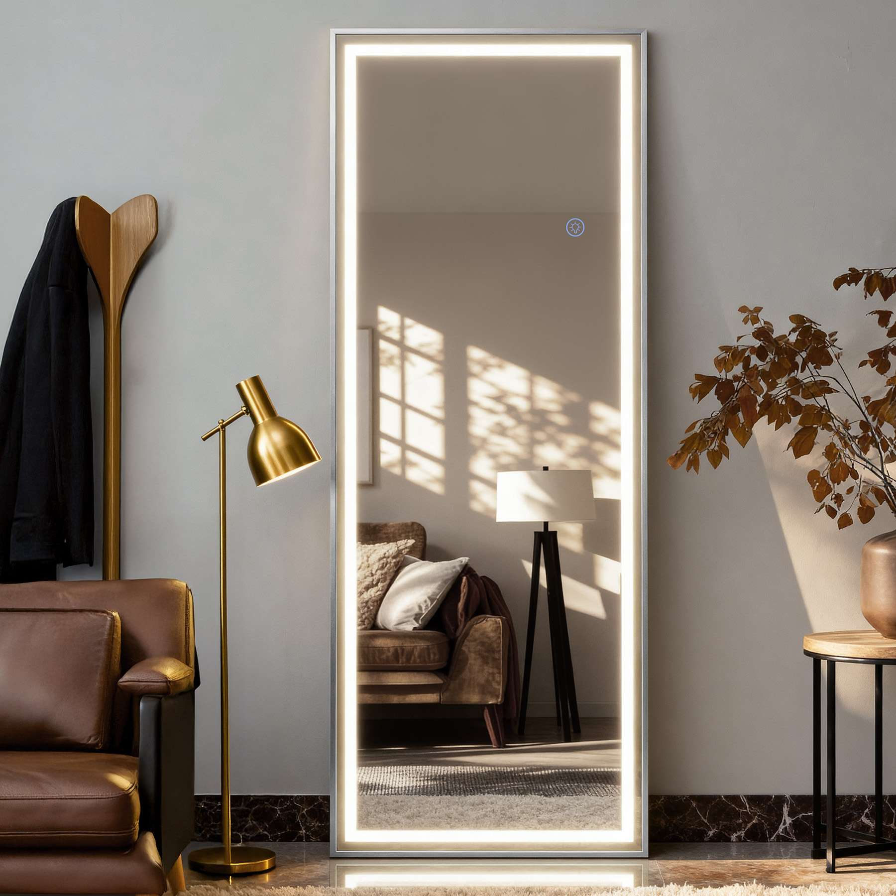 Ein Ganzkörperspiegel mit beleuchtetem Rand. Links ein Garderobenständer und eine Stehlampe. Ein Sofa spiegelt sich.