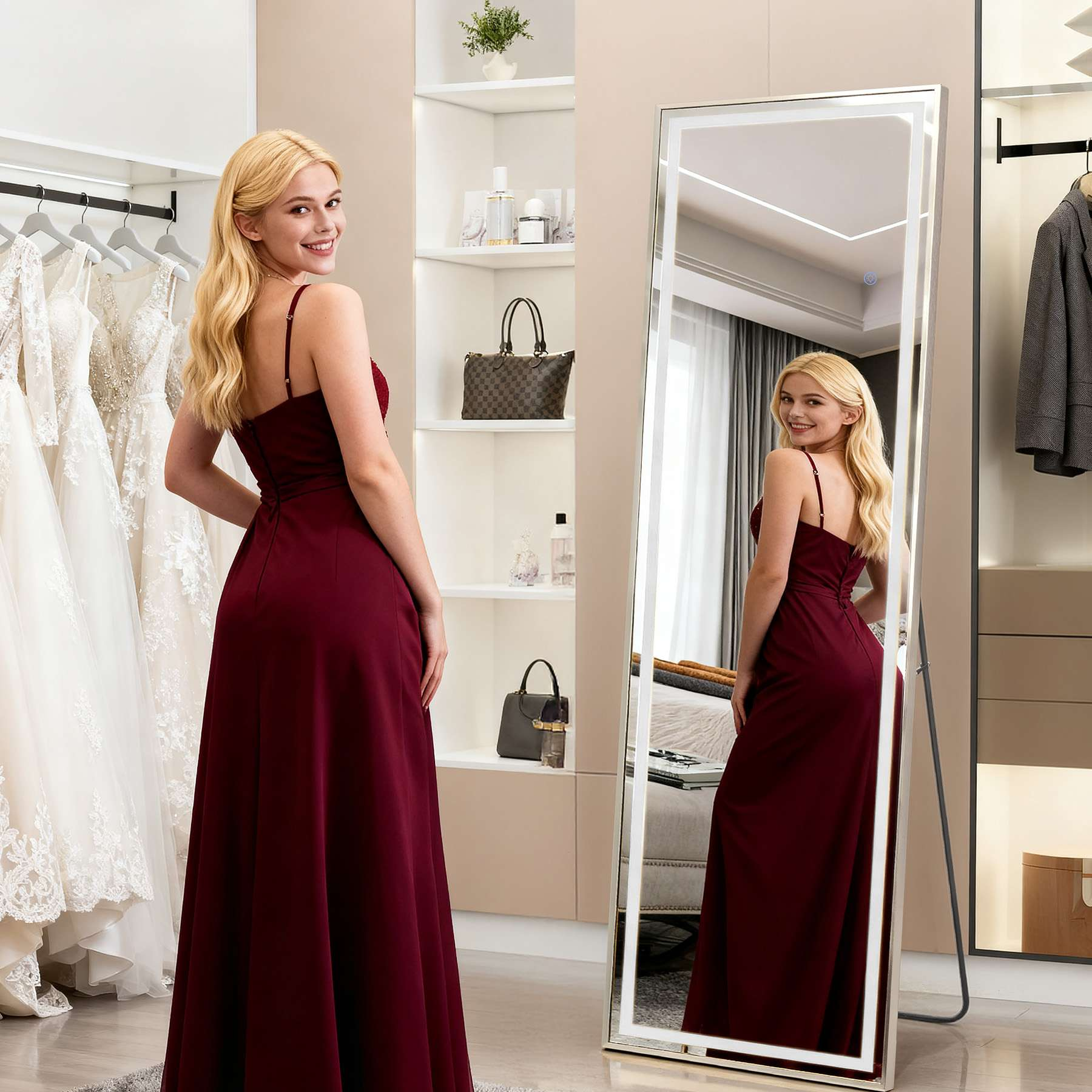 Eine Frau in einem bordeauxfarbenen Kleid posiert. Ein Spiegel spiegelt sie wider. Im Hintergrund hängen Brautkleider.