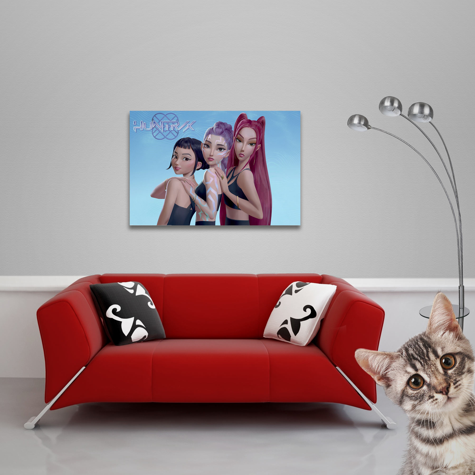 Rotes Sofa mit Kissen und einem Bild von drei Frauen. Eine Katze im Vordergrund und eine Lampe.