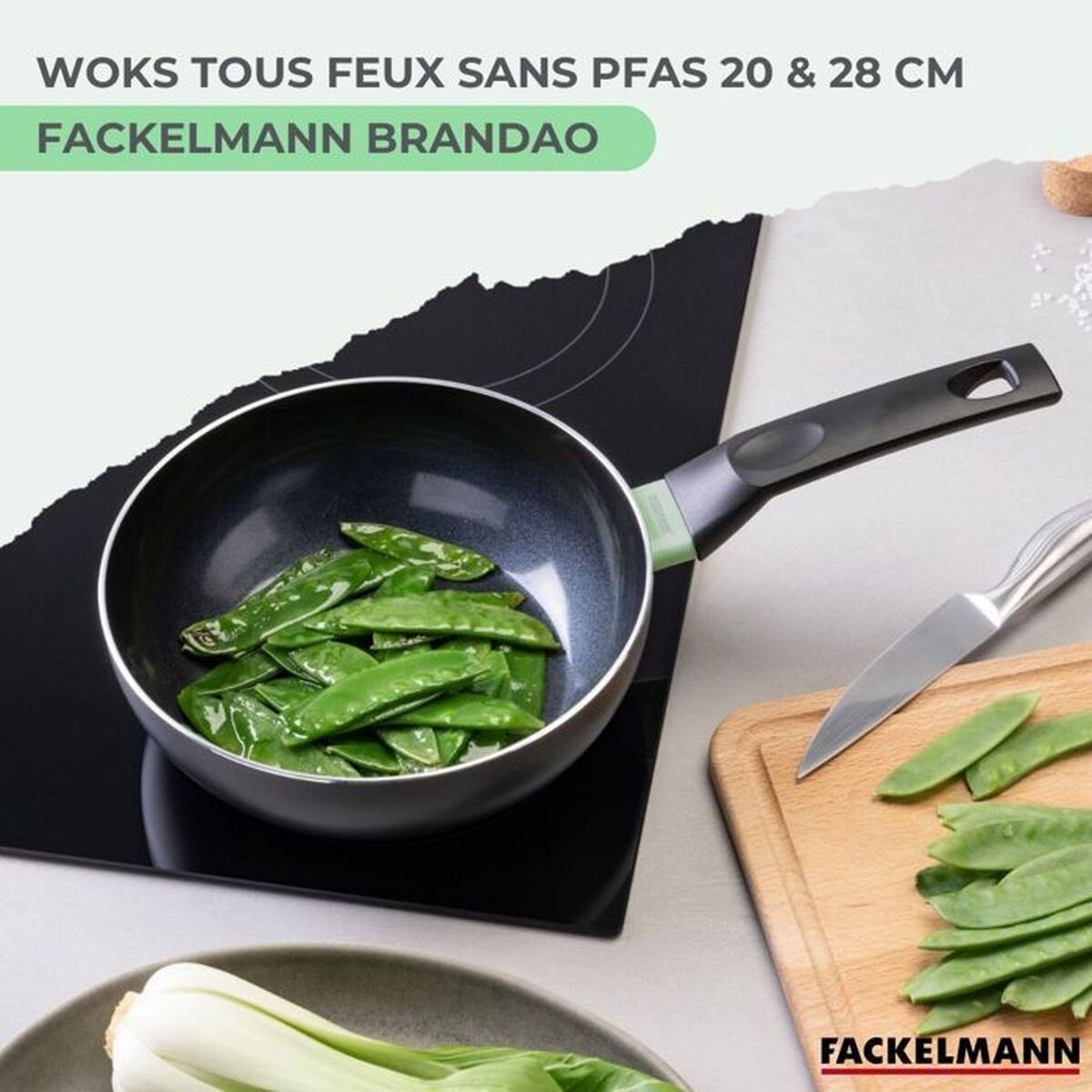 Un wok pieno di piselli mangiatutto verdi è posto su un piano cottura nero. Un tagliere con piselli tagliati e un coltello sono accanto.