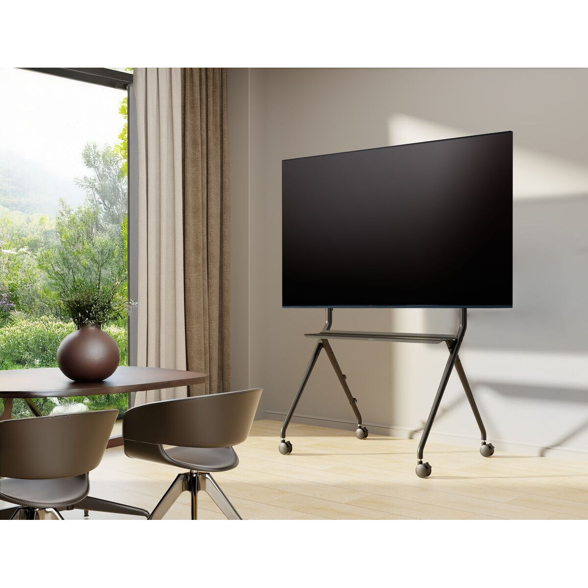 Ein modernes Wohnzimmer mit einem großen Fernseher auf einem rollenden Ständer. Ein Tisch mit Stühlen und ein Fenster mit Aussicht sind ebenfalls vorhanden.