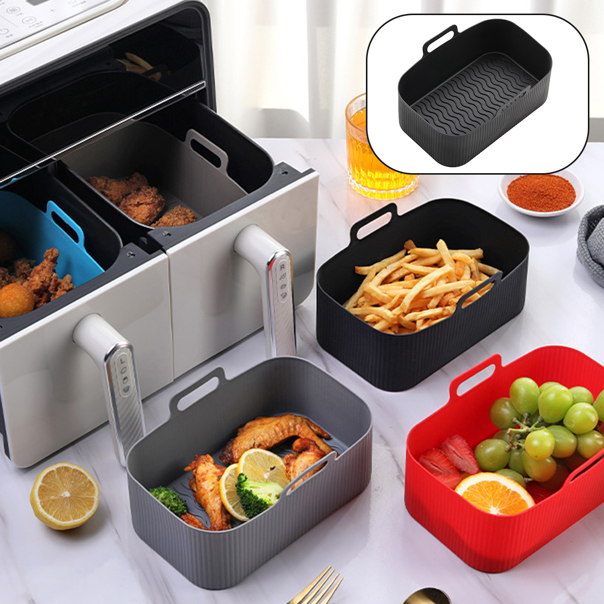 Ein Airfryer mit Essen, dazu Behälter mit Pommes, Flügeln und Obst. Ein Glas Flüssigkeit und Gewürze sind ebenfalls vorhanden.
