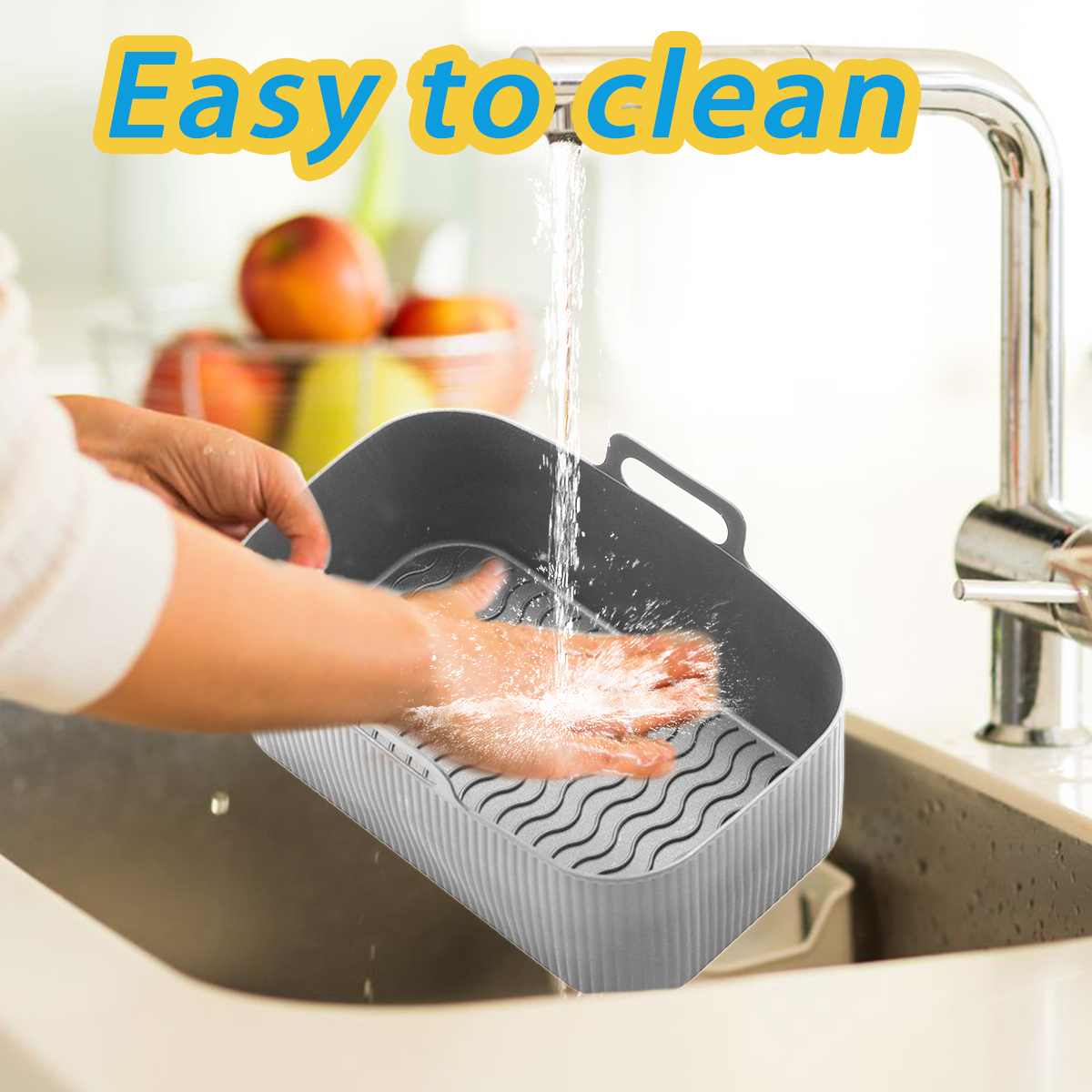 Eine Person wäscht einen grauen Korb in einem Küchenbecken unter fließendem Wasser. Der Korb ist mit 'Leicht zu reinigen' beschriftet.