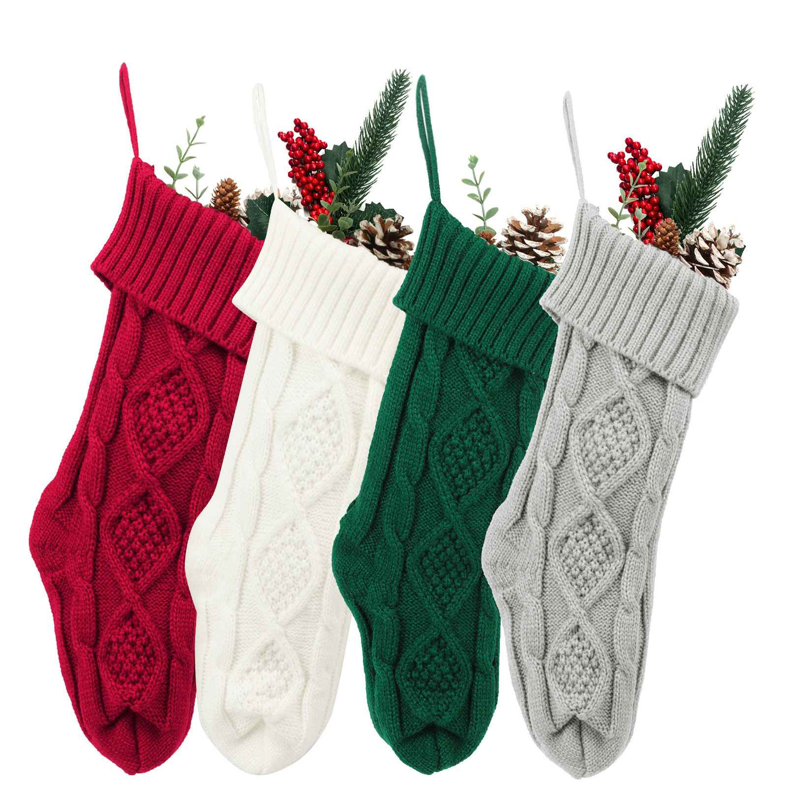 Vier gestrickte Weihnachtsstrümpfe in Rot, Weiß, Grün und Grau, gefüllt mit Tannenzapfen und Beeren.
