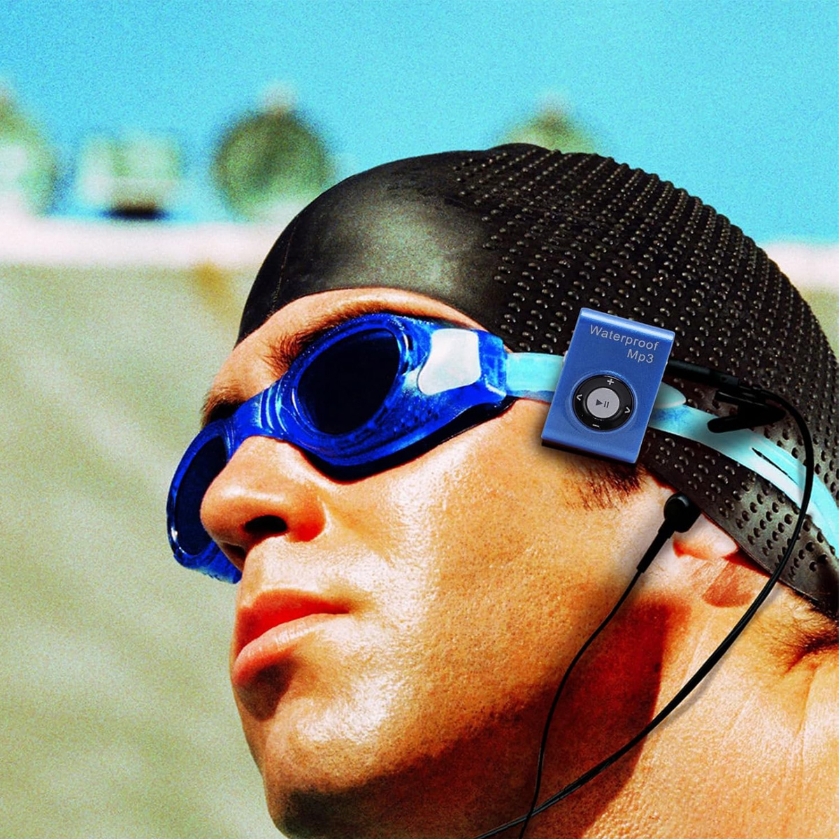 Mann mit Schwimmbrille, Badekappe und blauem wasserdichten MP3-Player. Schwarze Kopfhörer sind angeschlossen.