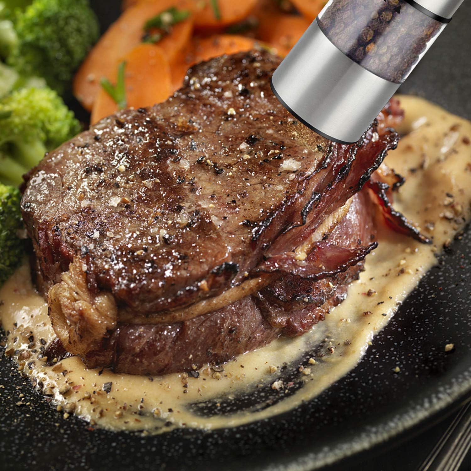 Ein Steak mit Soße auf einem Teller, wird mit einer Pfeffermühle gepfeffert. Brokkoli und Karotten sind im Hintergrund.