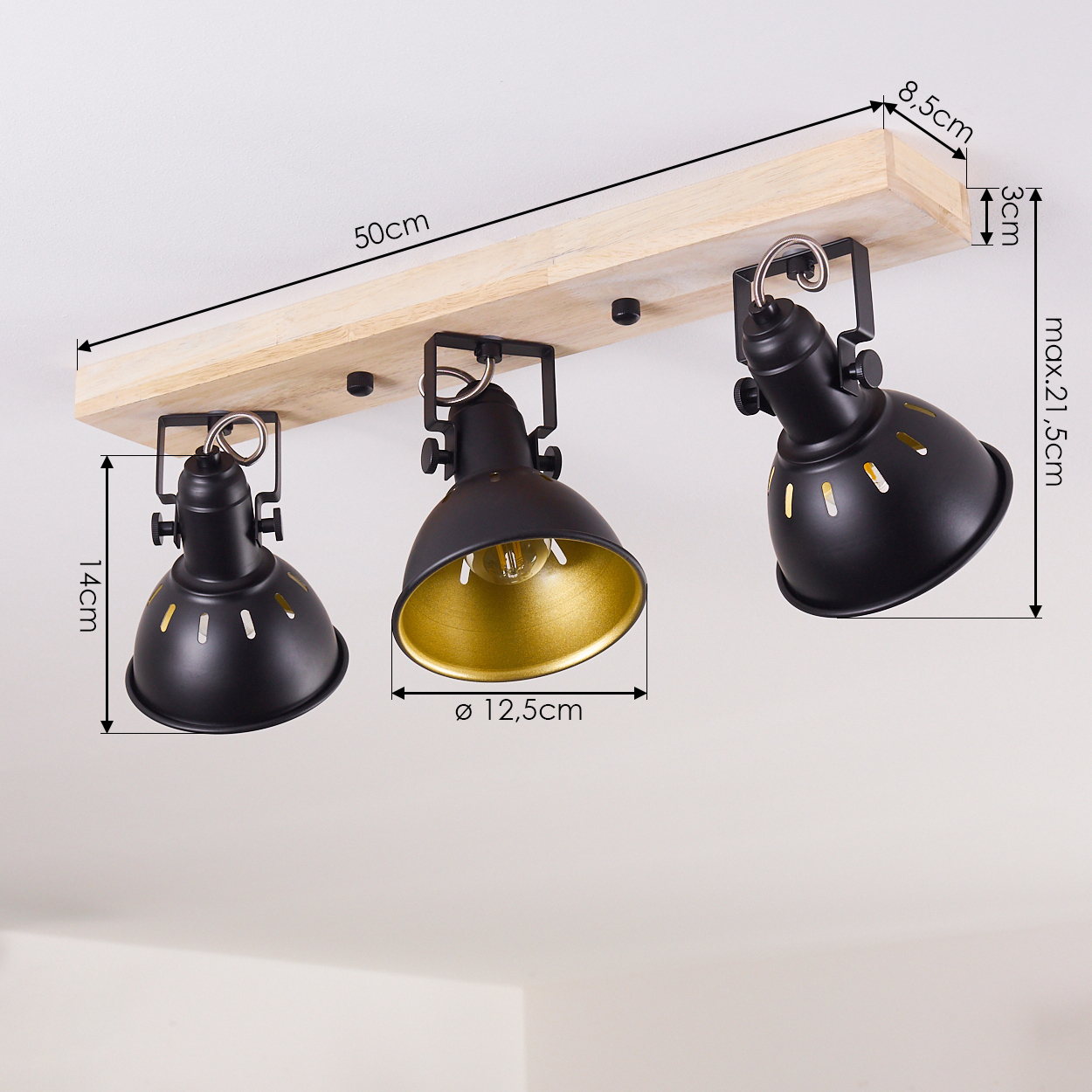 Schwarze und goldene Strahler mit drei Lichtern an einem Holzbalken. Abmessungen sind mit Pfeilen angegeben.