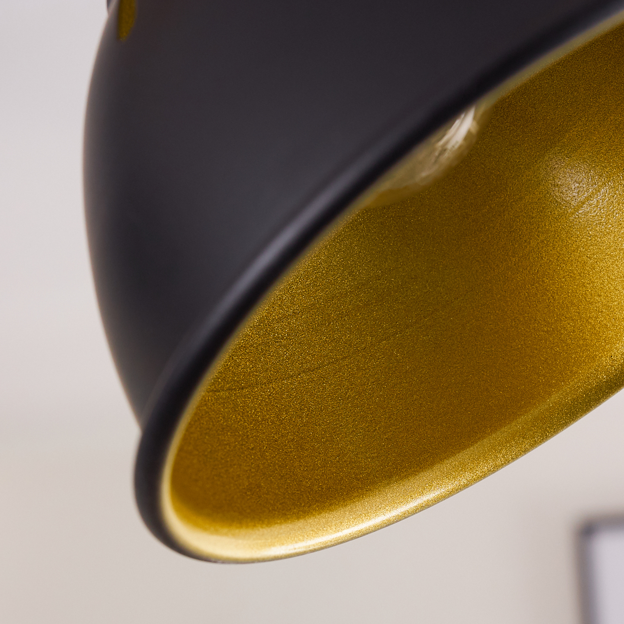 Nahaufnahme eines schwarzen Lampenschirms mit goldfarbenem Innenraum. Der Hintergrund ist verschwommen.