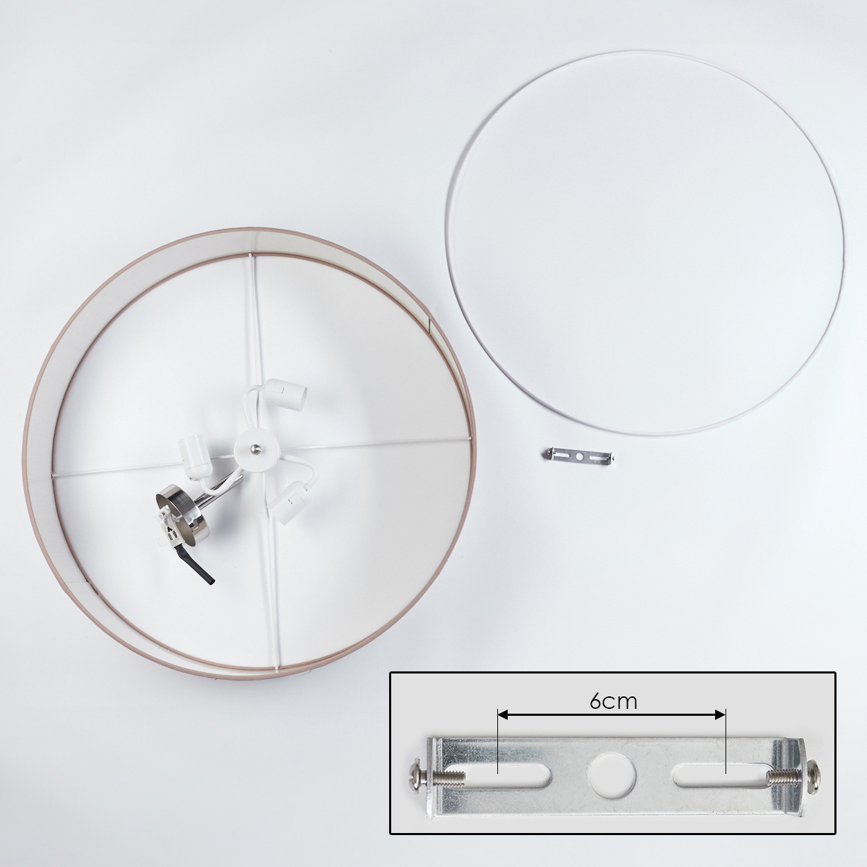 Draufsicht auf eine zerlegte Lampe. Zu den Komponenten gehören ein Lampenschirmrahmen, eine Halterung, elektrische Komponenten und ein Lampenschirm.