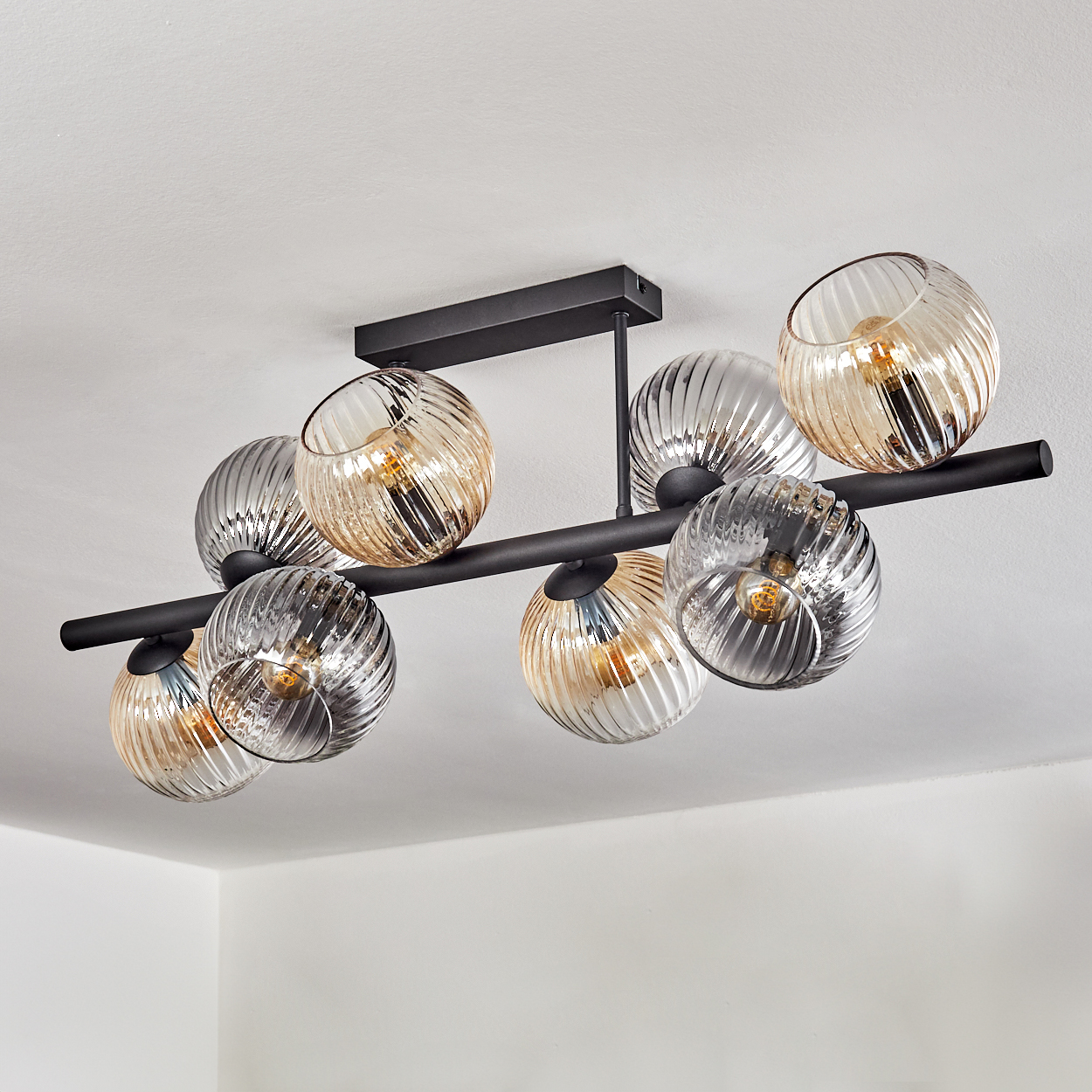 Eine moderne Deckenleuchte mit acht Glasschirmen, abwechselnd bernsteinfarben und silberfarben, auf einem schwarzen Metallrahmen.