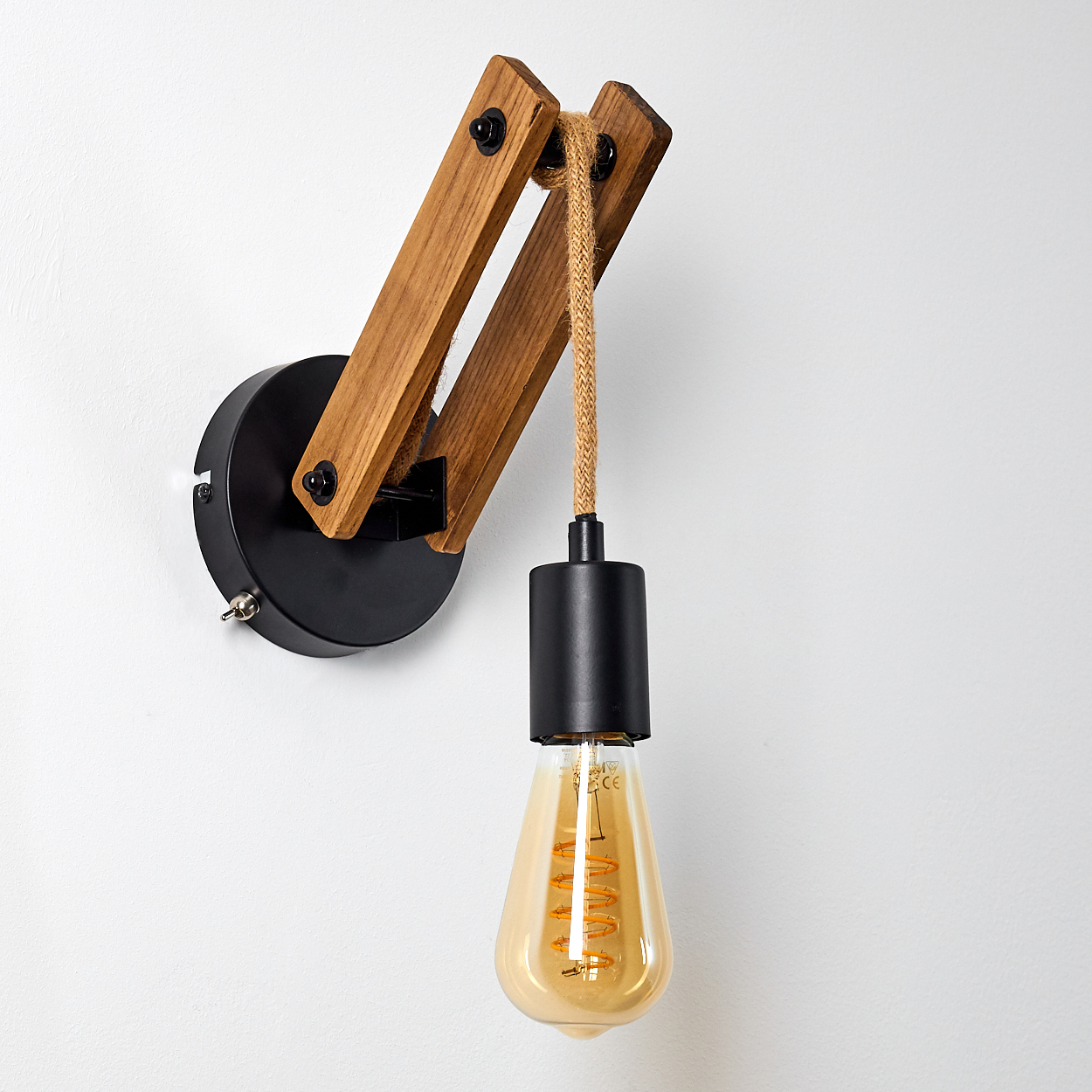Eine Wandlampe mit Holzbalken, einem schwarzen Sockel und einer Glühbirne. Die Glühbirne hat eine warme gelbe Farbe. Der Hintergrund ist weiß.