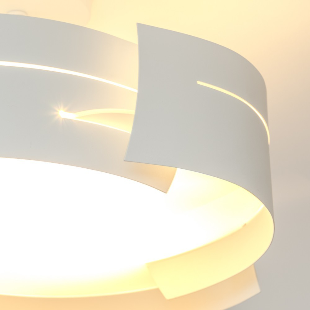 Eine moderne weiße Lampe mit gebogenen, geschichteten Schirmen. Licht scheint durch die Aussparungen und erhellt den Raum.
