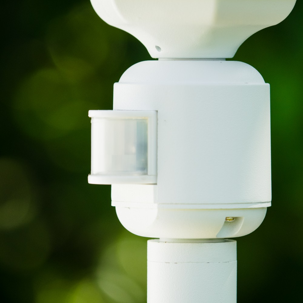 Nahaufnahme eines weißen, zylindrischen Objekts mit Sensor. Der Hintergrund ist verschwommenes grünes Laub.