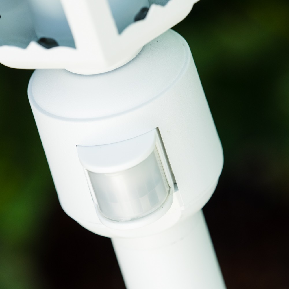 Nahaufnahme eines weißen Sensorelements. Das Gerät hat eine runde Form mit einem transparenten Sensor vor verschwommenem grünem Hintergrund.