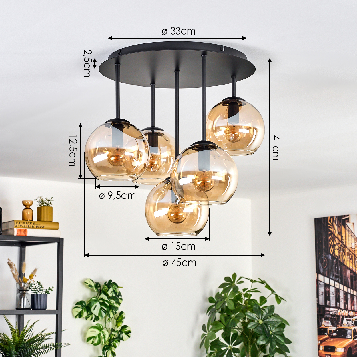 Eine moderne Deckenlampe mit fünf bernsteinfarbenen Glaskugeln. Maße sind angegeben. Pflanzen und Dekoration sind im Hintergrund.