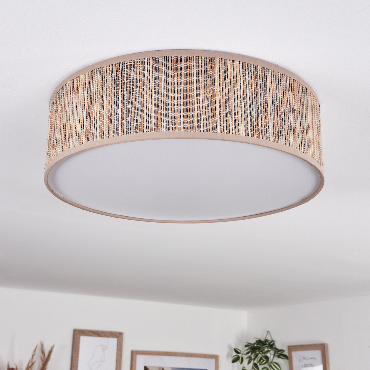 Eine runde Deckenlampe mit gewebtem Rattanschatten. Die Lampe hat einen weißen, kreisförmigen Lichtdiffusor.
