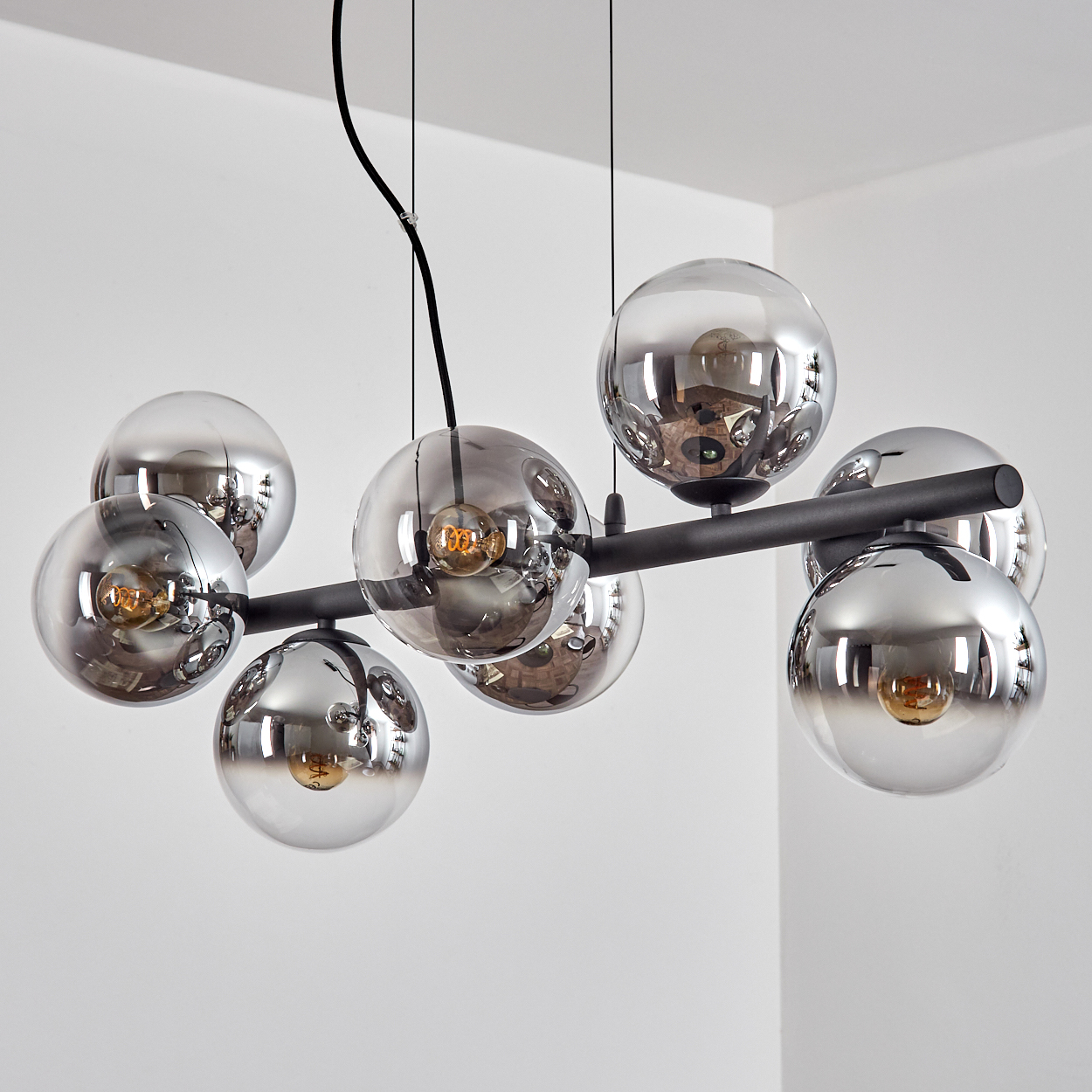 Eine moderne Deckenleuchte mit mehreren kugelförmigen Glasschirmen, die jeweils eine Glühbirne enthalten und von der Decke abgehängt sind.