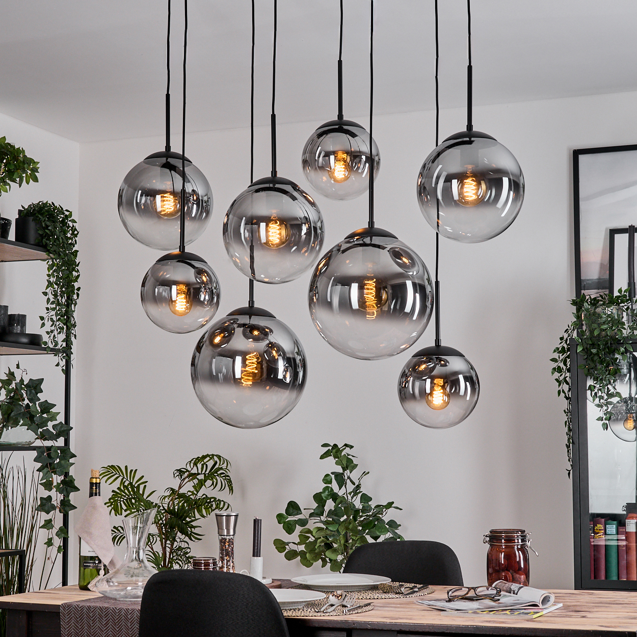 Esszimmer mit acht kugelförmigen Pendelleuchten. Tisch mit Pflanzen und Dekoration. Pflanzen im Hintergrund.