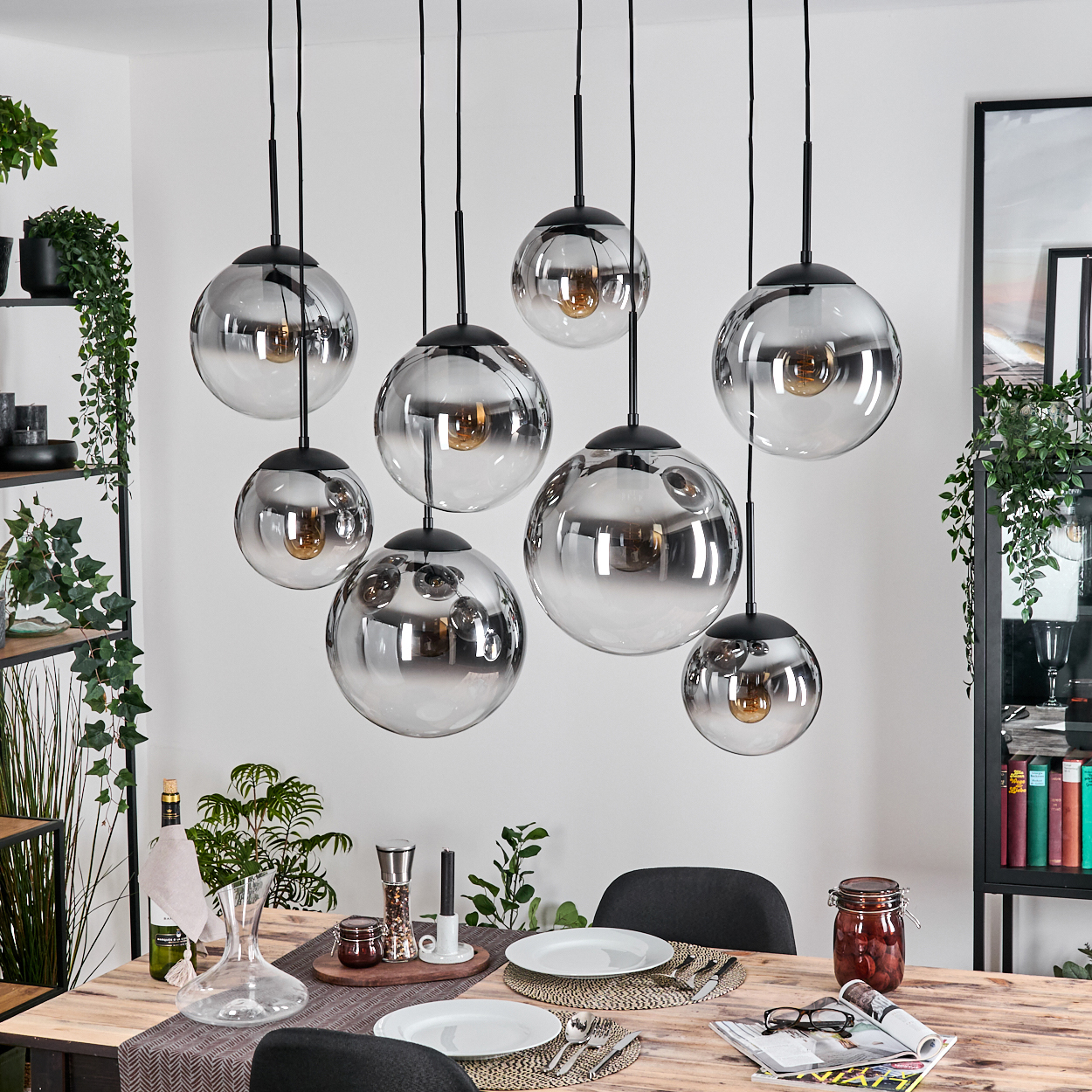 Esszimmer mit Holztisch. Acht Kugelleuchten hängen. Pflanzen und ein Schrank sind im Hintergrund.