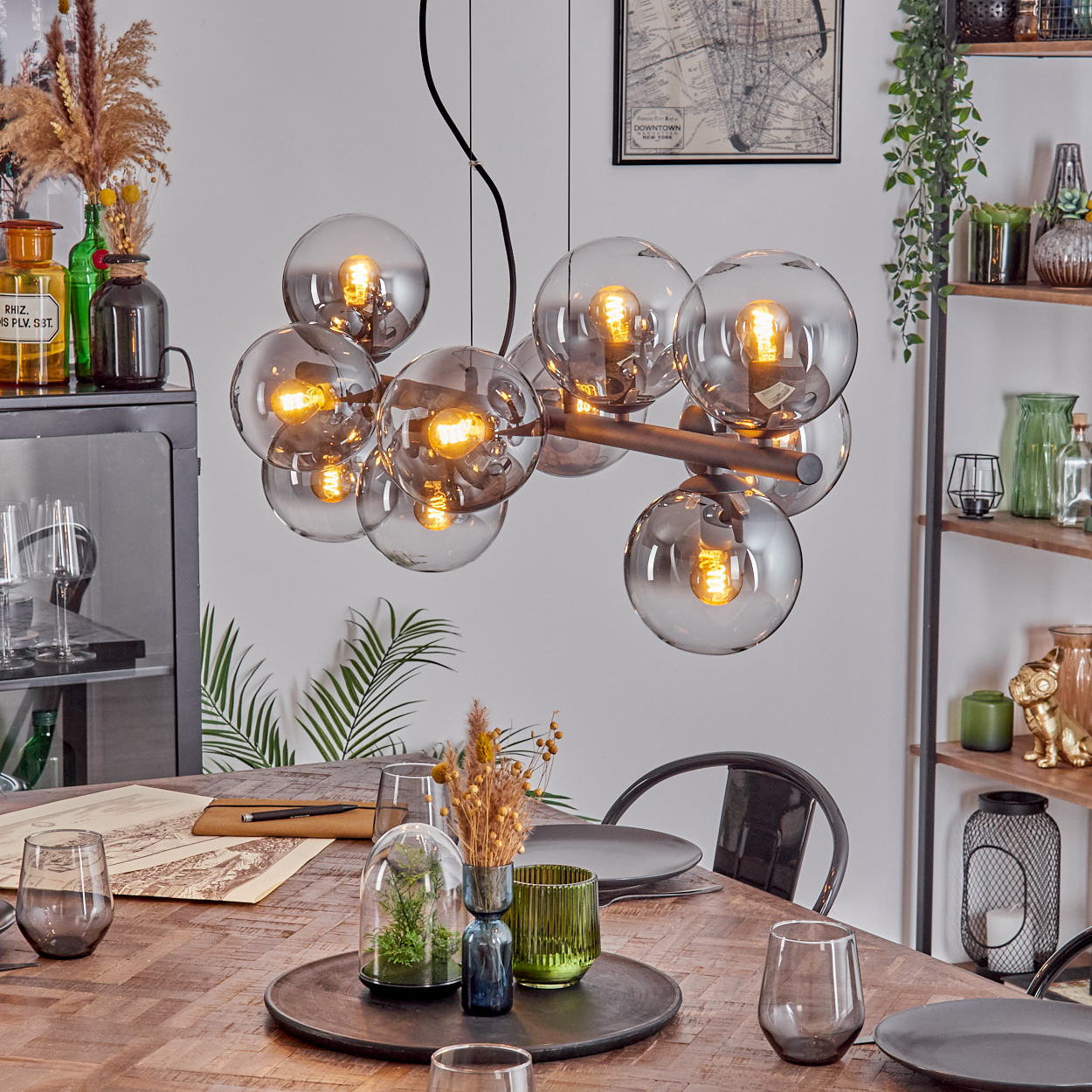 Ein Esszimmer mit Holztisch, moderner Leuchte mit Kugellampen und Dekorationen.