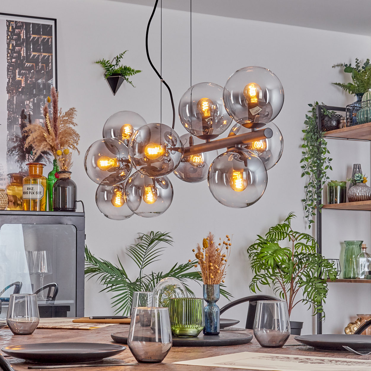 Esszimmer mit Holztisch, Gläsern, Tellern und einer dekorativen Leuchte mit Glaskugeln.