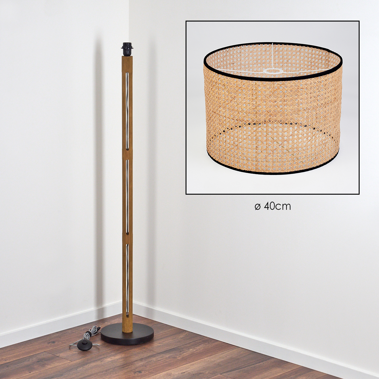 Eine Stehlampe aus Holz mit einem gewebten Lampenschirm. Der Lampenschirm ist zylindrisch, mit schwarzem Rand. Die Lampe steht in einer weißen Ecke.
