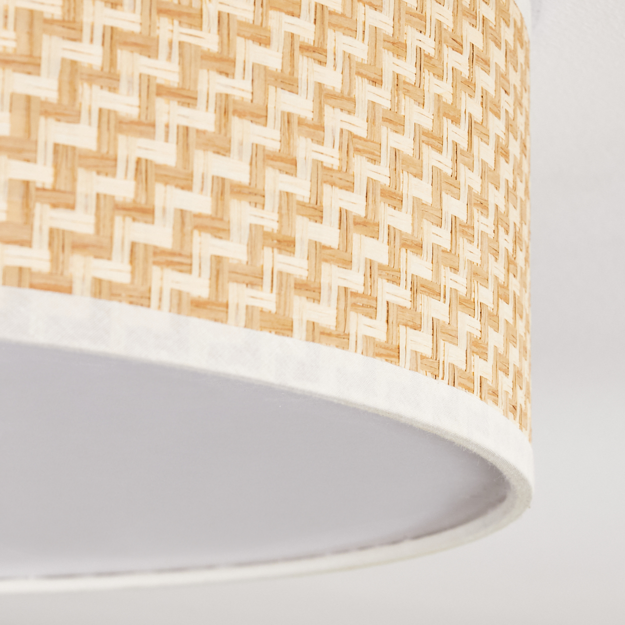Nahaufnahme einer Lampe. Gewebter Bambusschatten mit weißem Rand. Der Boden der Lampe ist weiß. Der Hintergrund ist weiß.