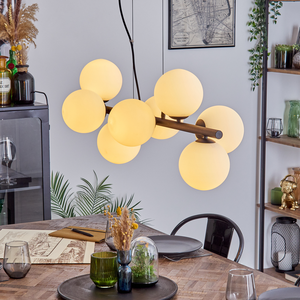 Ein Esszimmer mit Holztisch, moderner Kronleuchter mit Kugellichtern und verschiedene Dekorationsgegenstände.