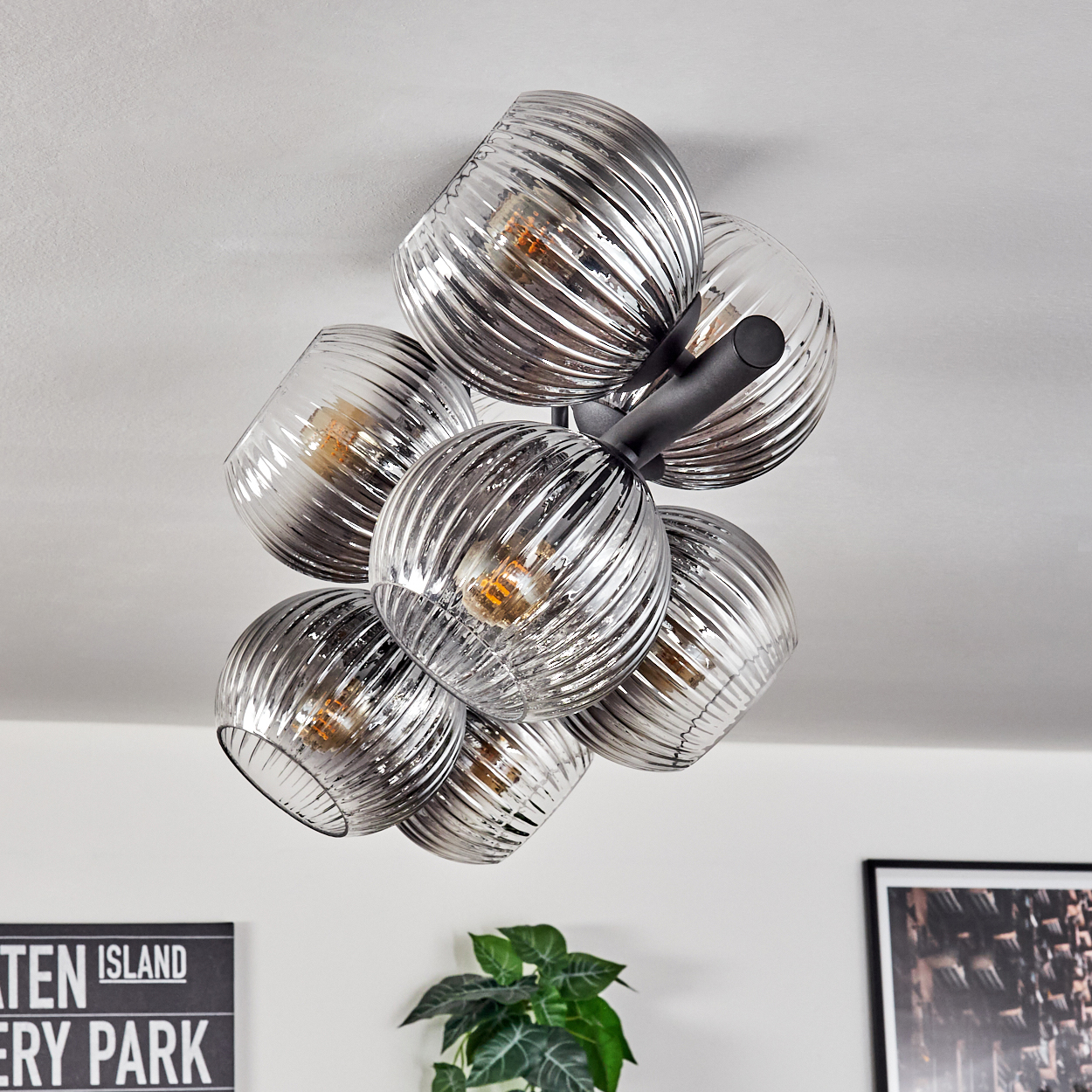 Moderne Deckenleuchte mit mehreren Glaskugeln. Jede Kugel hat eine strukturierte Oberfläche und enthält ein warmes Licht. Schwarze Metallarme tragen sie.