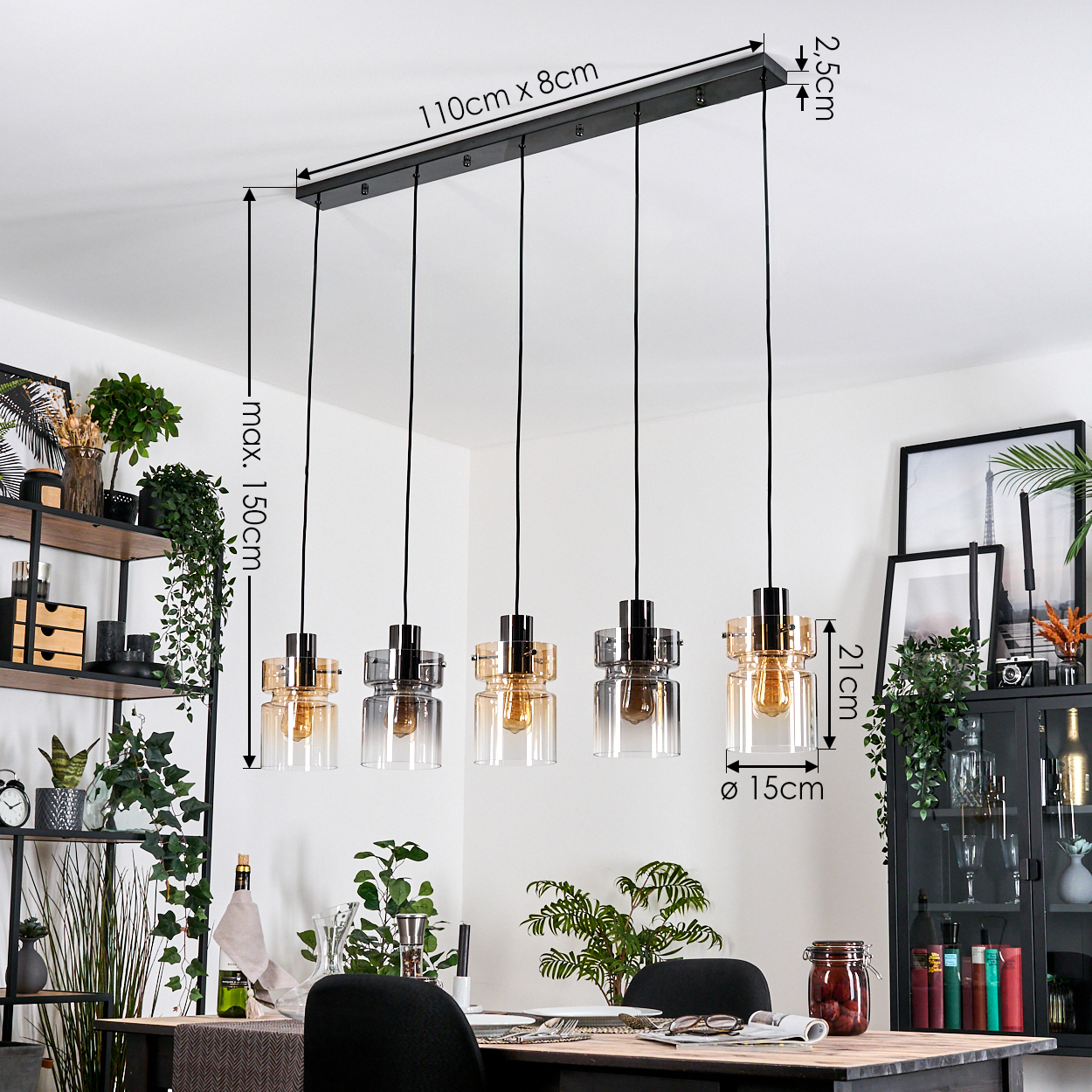 Ein Esszimmer mit schwarzer Leuchte, Hängelampen, einem Holztisch, Stühlen, Pflanzen und einem schwarzen Schrank mit Dekor.