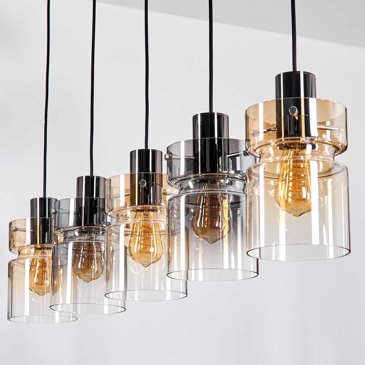 Sechs Pendelleuchten mit Glasschirmen und Edison-Glühbirnen hängen vor weißem Hintergrund.