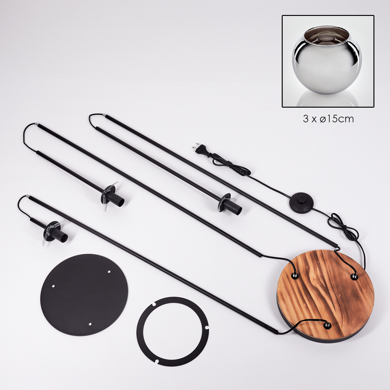Zerlegte Lampenkomponenten. Schwarze Stäbe, Holzsockel, Metallring und eine silberne Schale in der Ecke. Weißer Hintergrund.