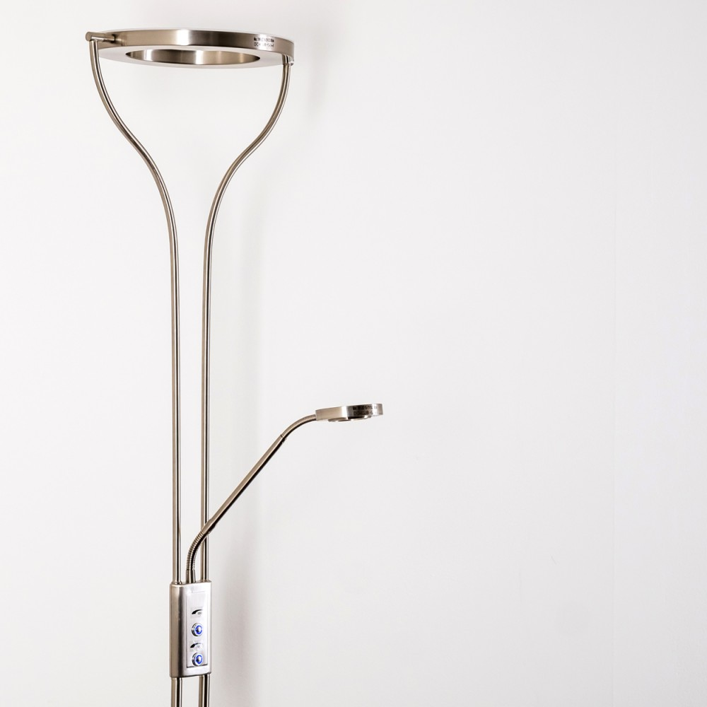 Eine moderne silberne Stehlampe mit rundem Kopf und einer verstellbaren kleineren Lampe. Der Hintergrund ist eine weiße Wand.