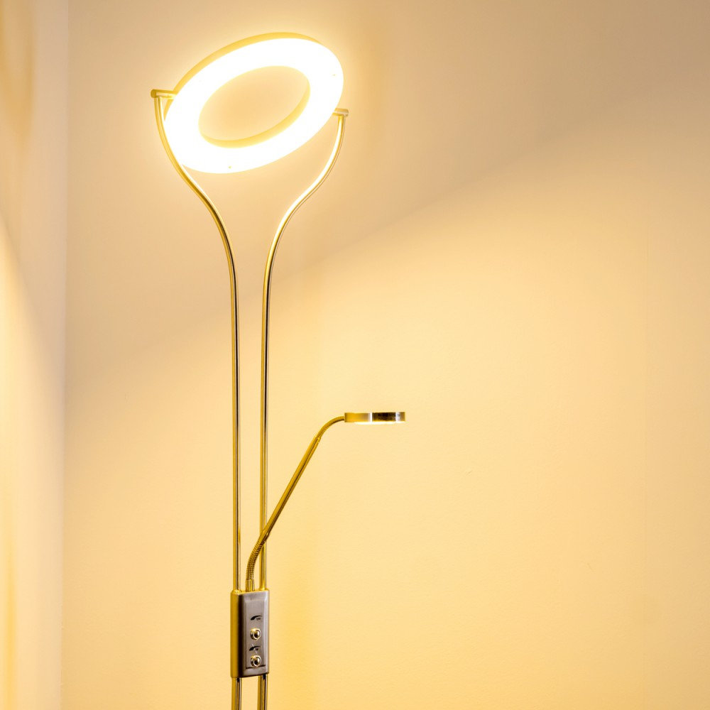 Eine goldene Stehlampe mit ringförmigem Licht oben und kleinem Licht unten. Der Hintergrund ist gelb.