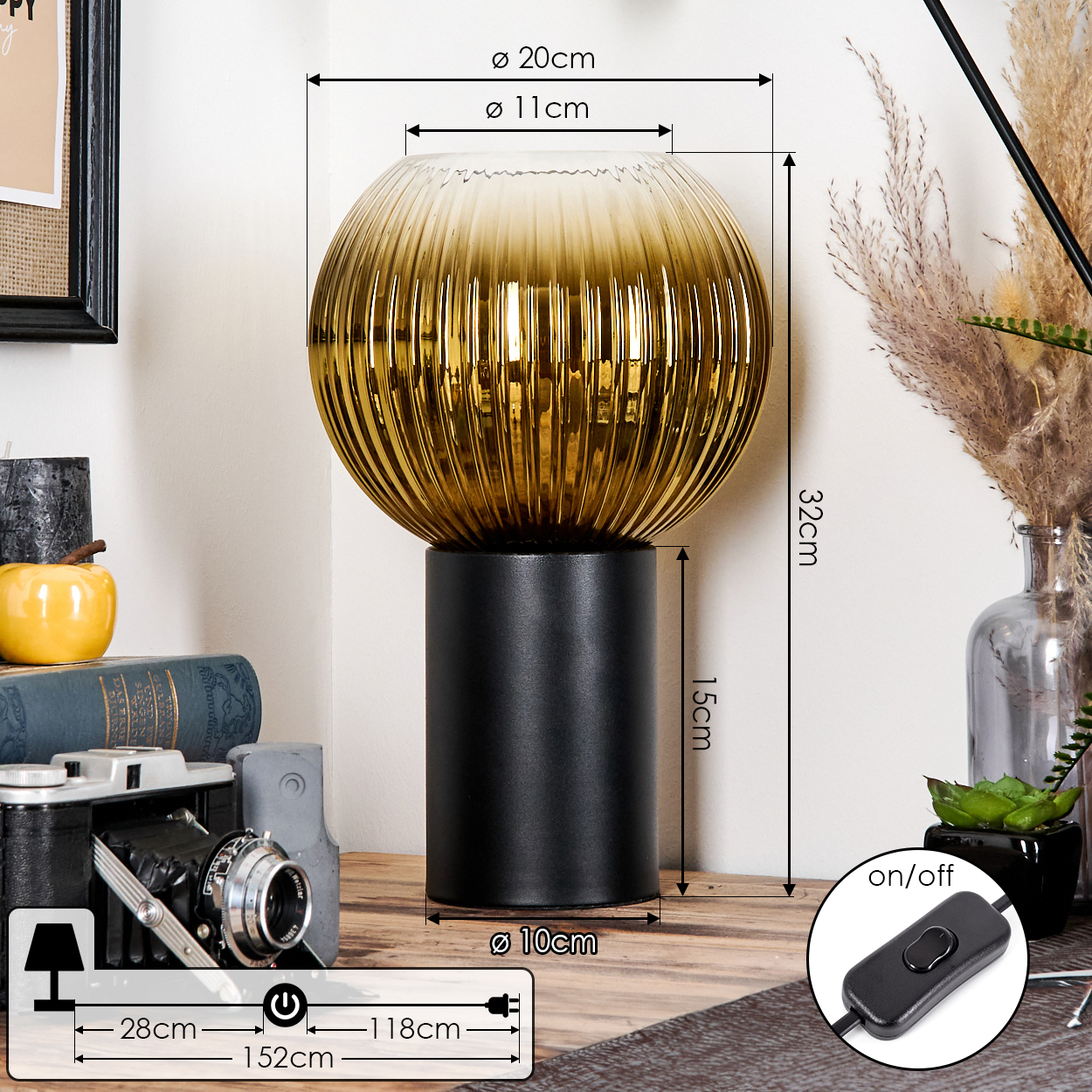 Eine dekorative Lampe mit schwarzem Sockel und geriffeltem, bernsteinfarbenem Glasschirm. Sie steht auf einer Holzoberfläche mit anderen Objekten.