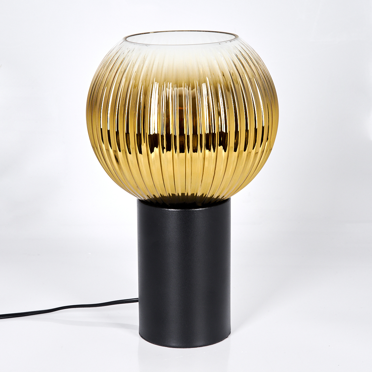 Eine moderne Lampe mit einem goldenen, geriffelten Glaskugelschirm auf einem schwarzen zylindrischen Sockel.