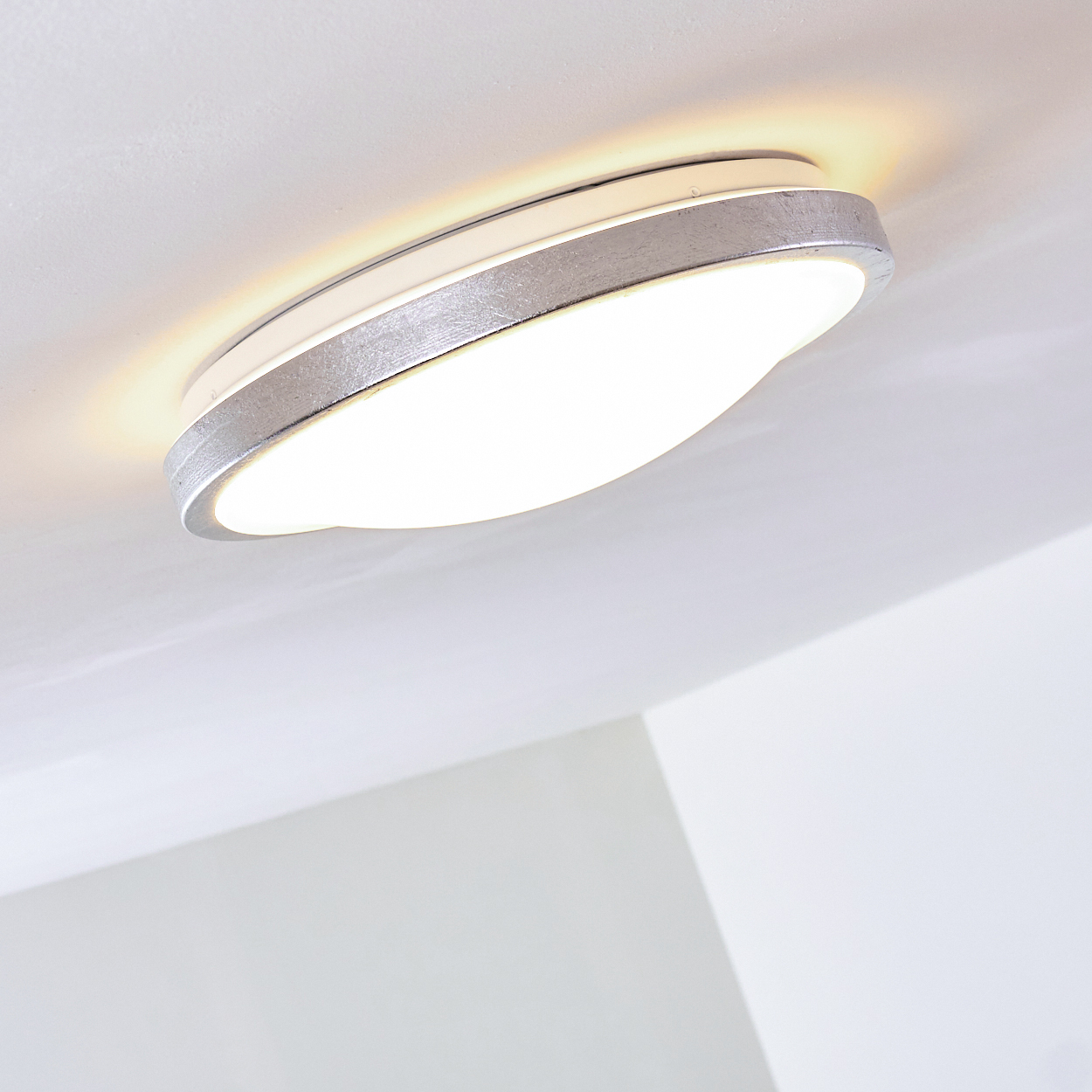 Eine moderne, ovale Deckenleuchte mit silbernem Metallrand und hellem weißem Licht.