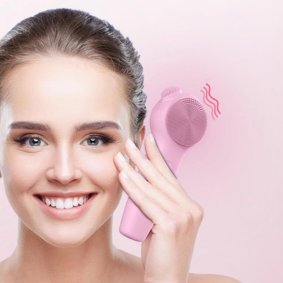 Eine lächelnde Frau hält eine rosa Gesichtsbürste an ihrer Wange. Rosa Wellenlinien zeigen die Funktion der Bürste. Rosa Hintergrund.